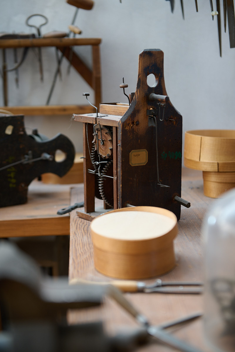 Ein Holzarbeitsplatz mit einem alten Werkzeug, einem mechanischen Gerät und verschiedenen Holzschalen.