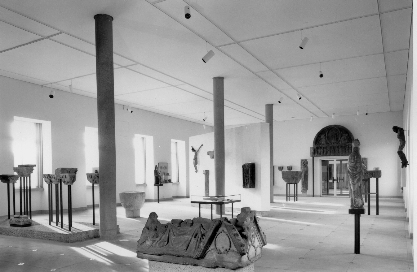 Innenansicht eines Museums mit antiken Skulpturen und Säulen auf hellen Fliesen.