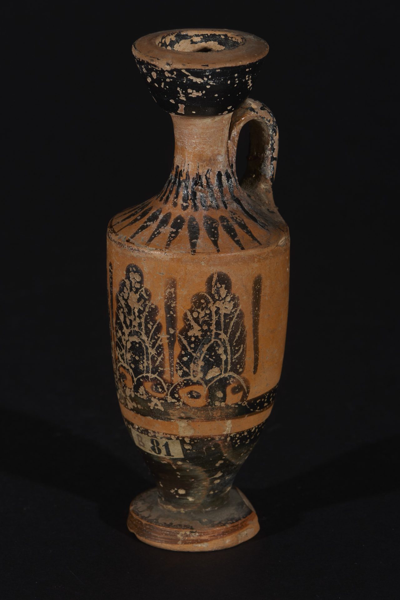 Antike Vase mit schwarzer und roter Ornamentik, schmalem Hals und rundem Fuß vor schwarzem Hintergrund.