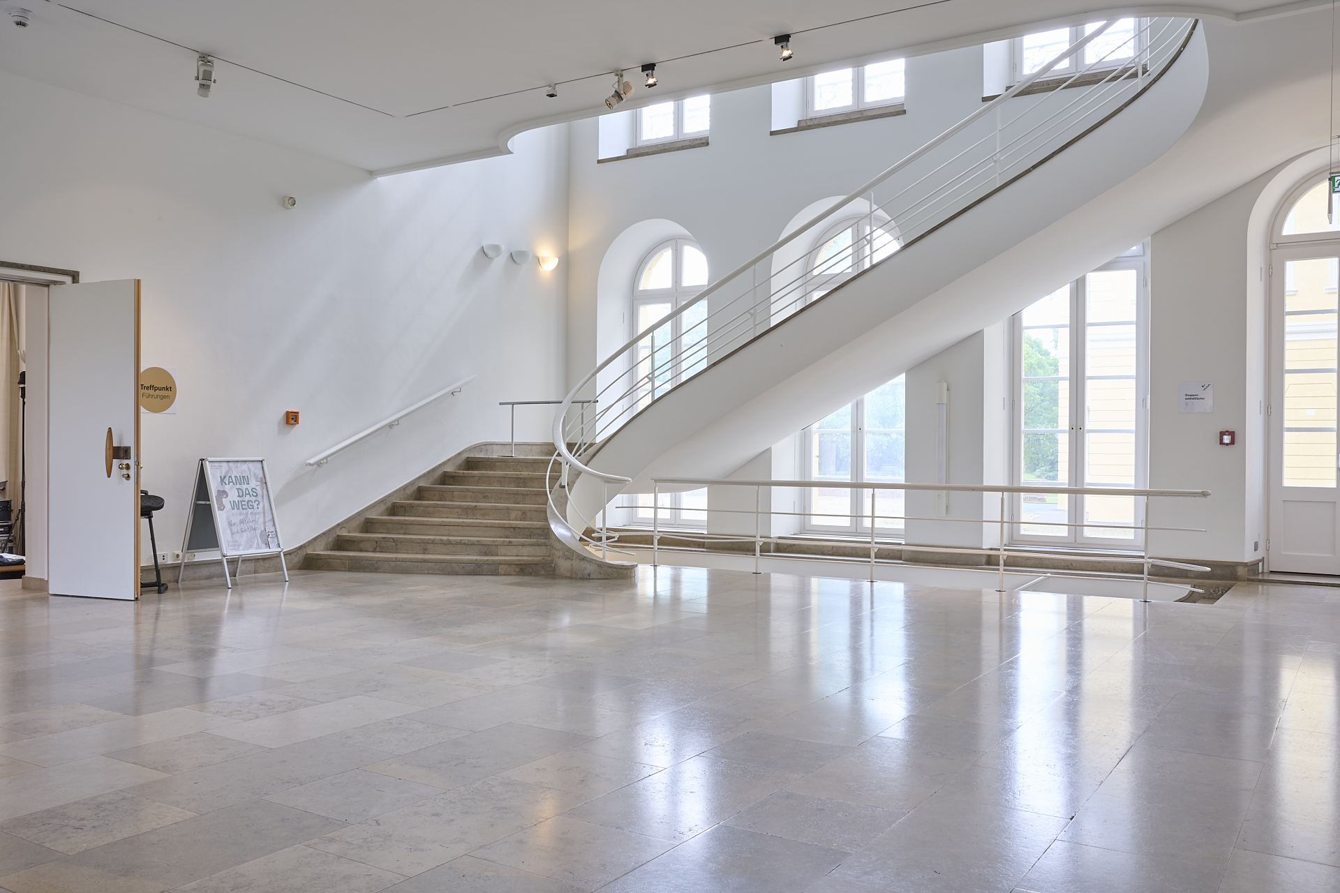 Ein leeres, weiträumiges Treppenhaus mit Marmorplattenboden.