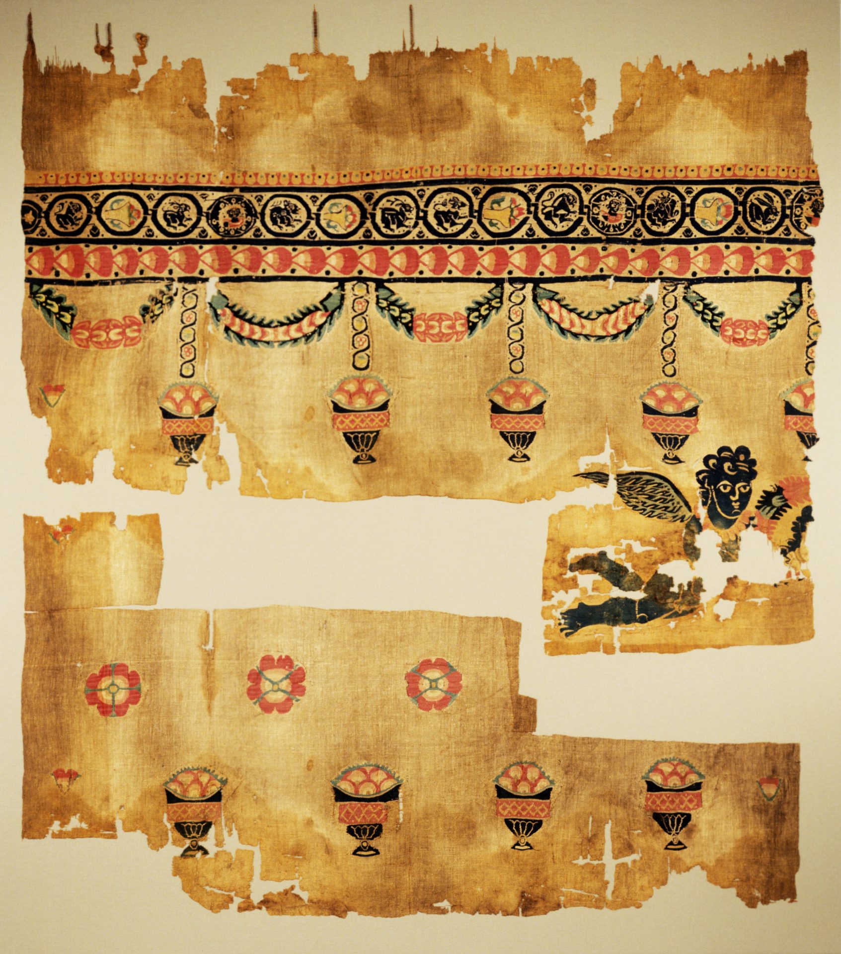 Antike Wandmalerei auf Stoff mit bunten Motiven wie Pflanzen, Gefäßen und figürlichen Darstellungen.