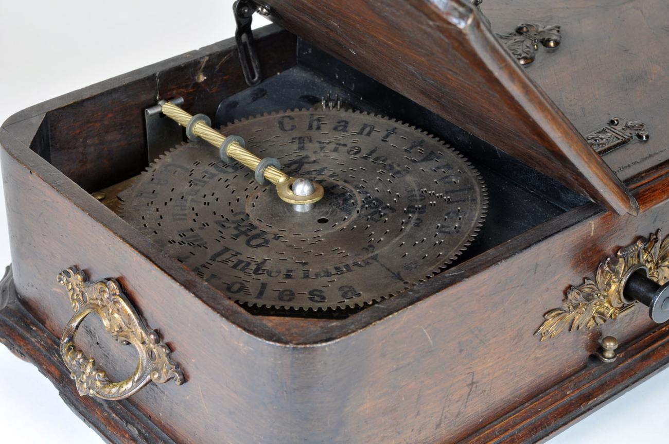 Antike Musikdose mit Metallmechanik und aufgedruckten Noten in elegantem Holzkasten.