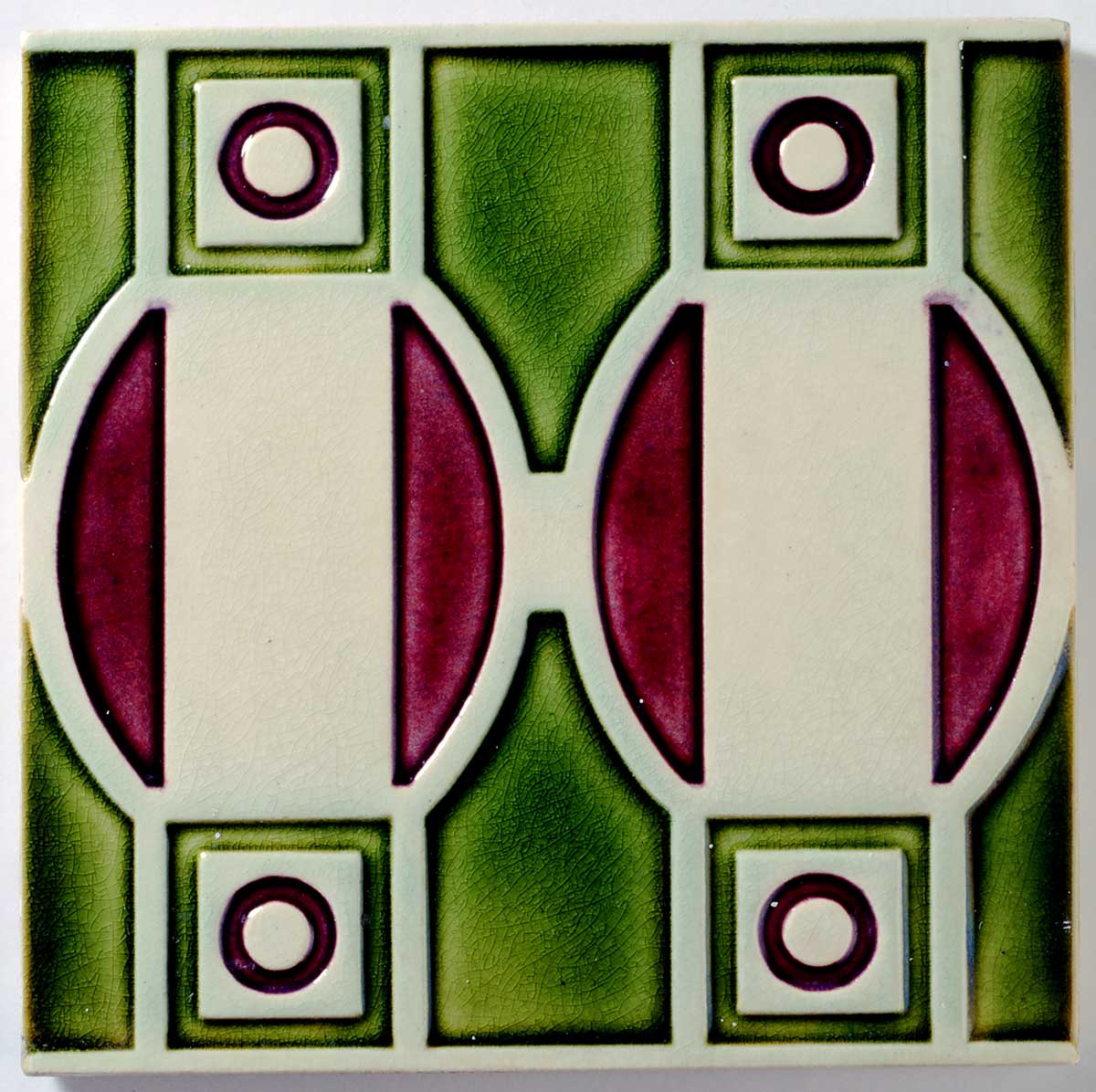 Bunte Fliese mit geometrischen Mustern in Grün, Weiß und Rot, bestehend aus Ovale und Kreise.