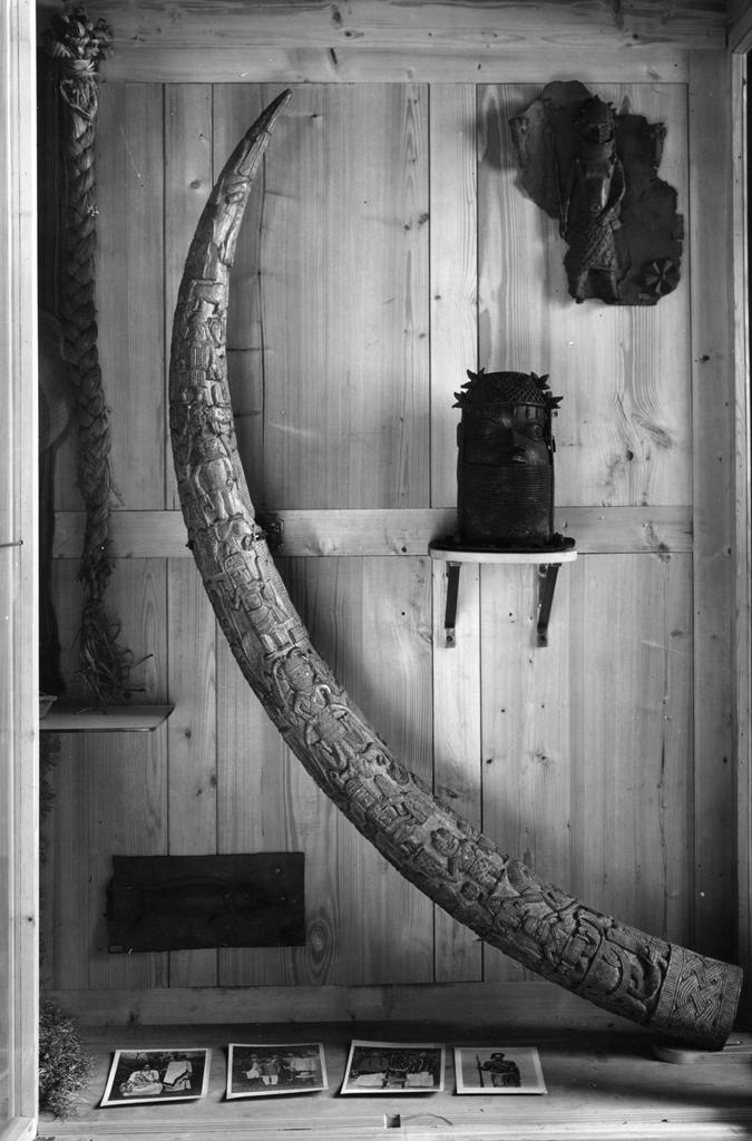 Historisches Ausstellungselement: geschnitztes Horn, Skulpturen und Fotos in einer Box aus Holz.