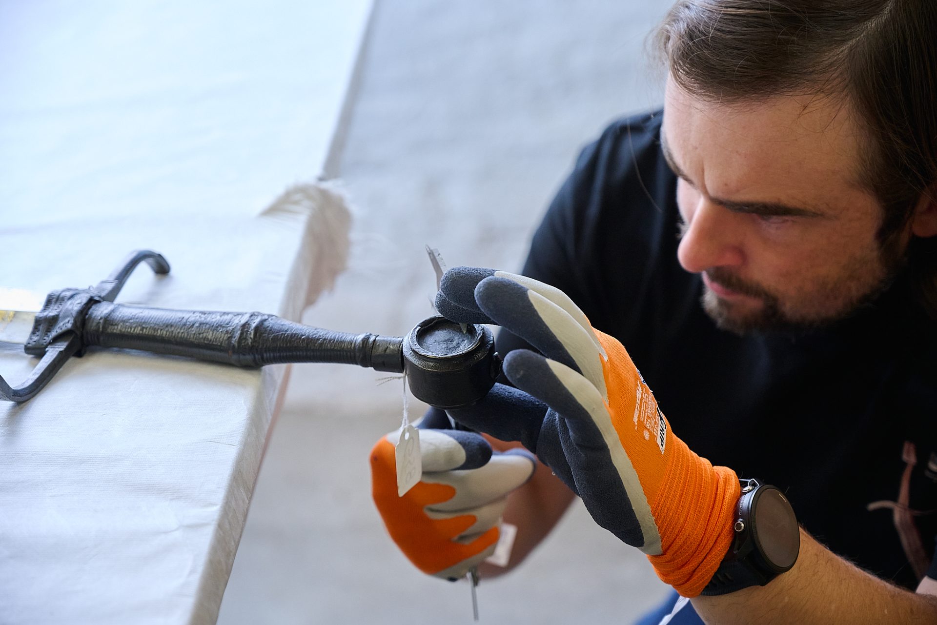 Eine Person in Handschuhen untersucht ein historisches Objekt auf einem Tisch.