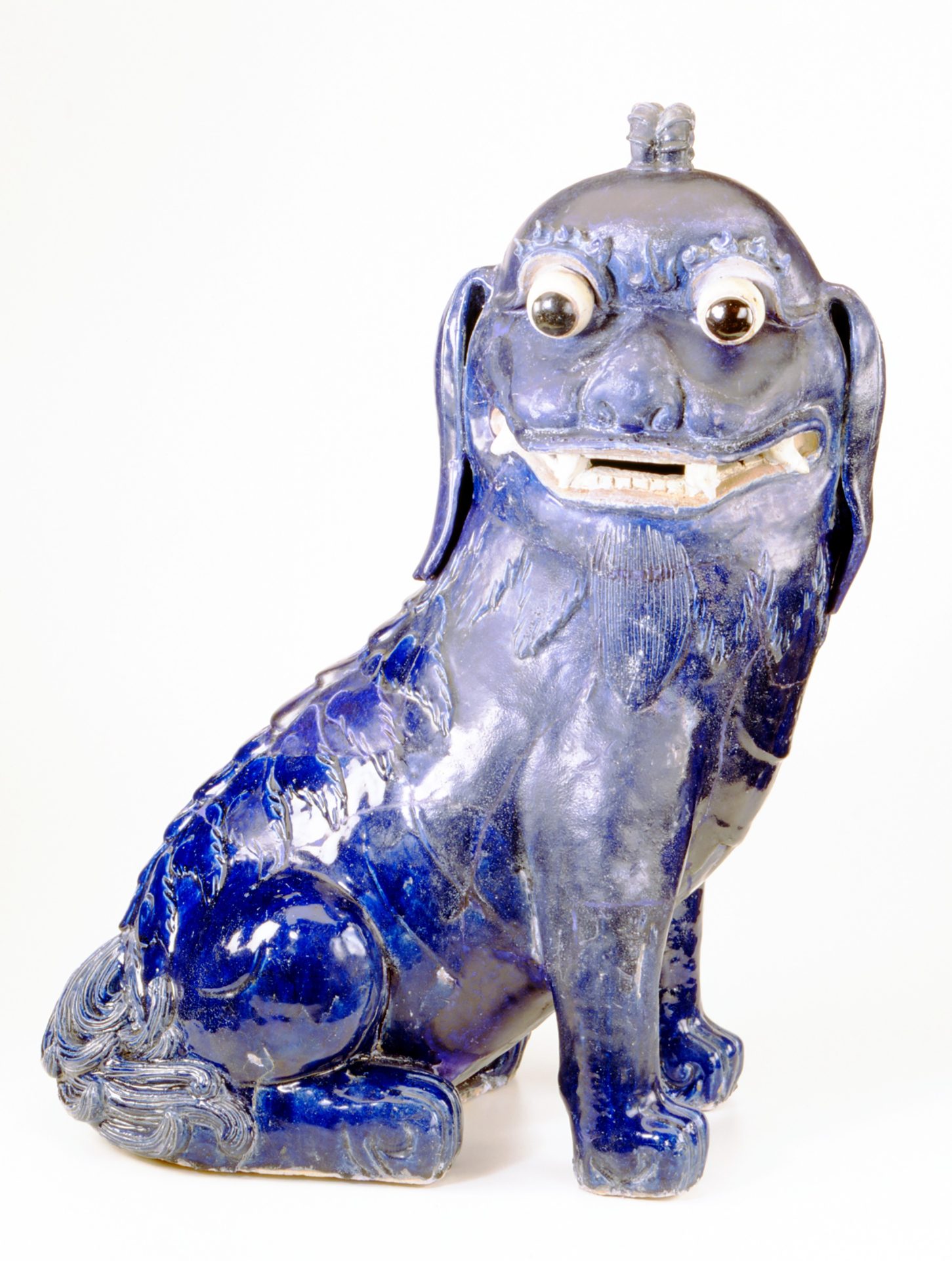Blau-weiße, detaillierte Keramik-Hundefigur mit großen Augen und schelmischem Ausdruck.