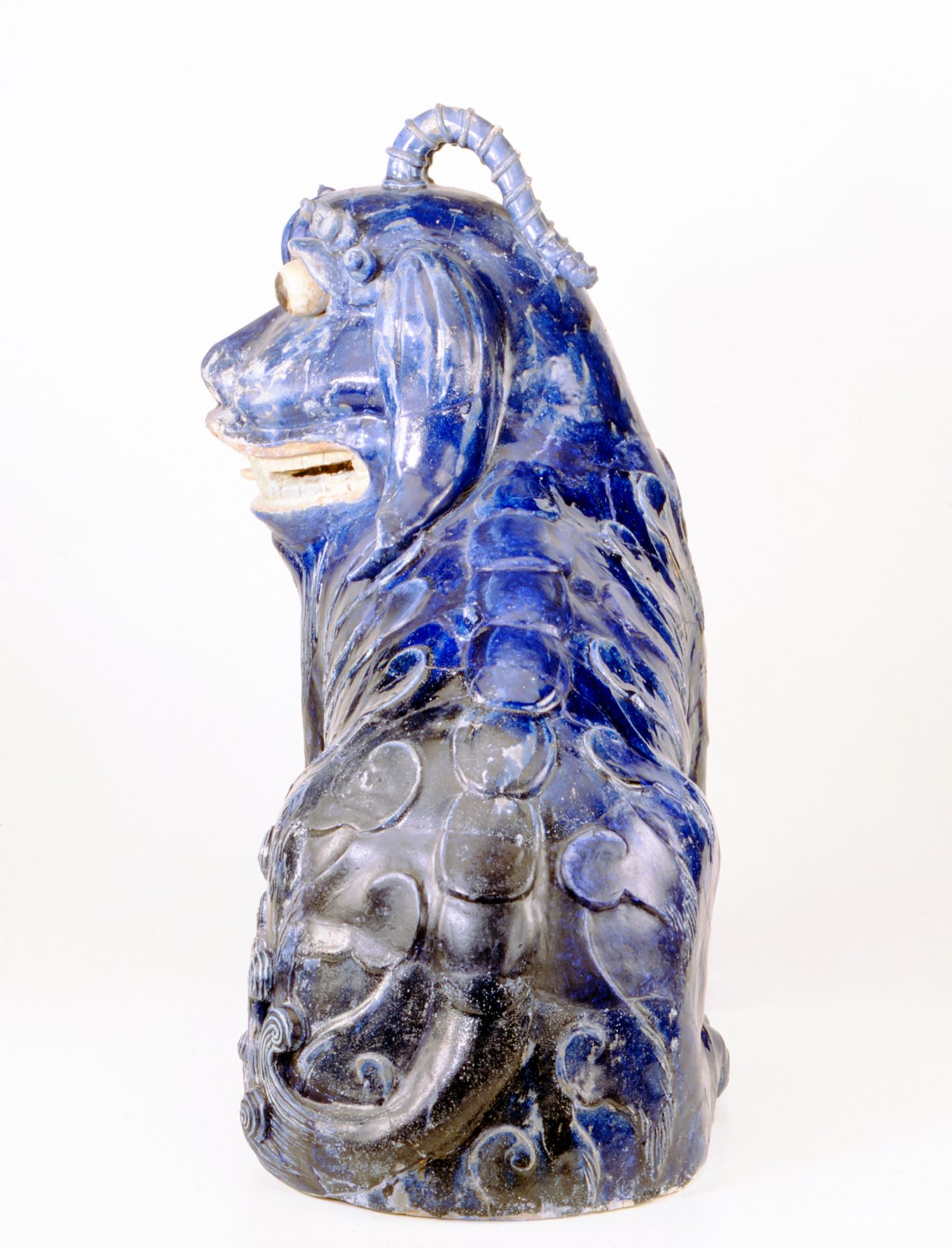 Blauer, keramischer Löwenkopf mit detaillierter Verzierung und spiralförmigem Ornament oben.