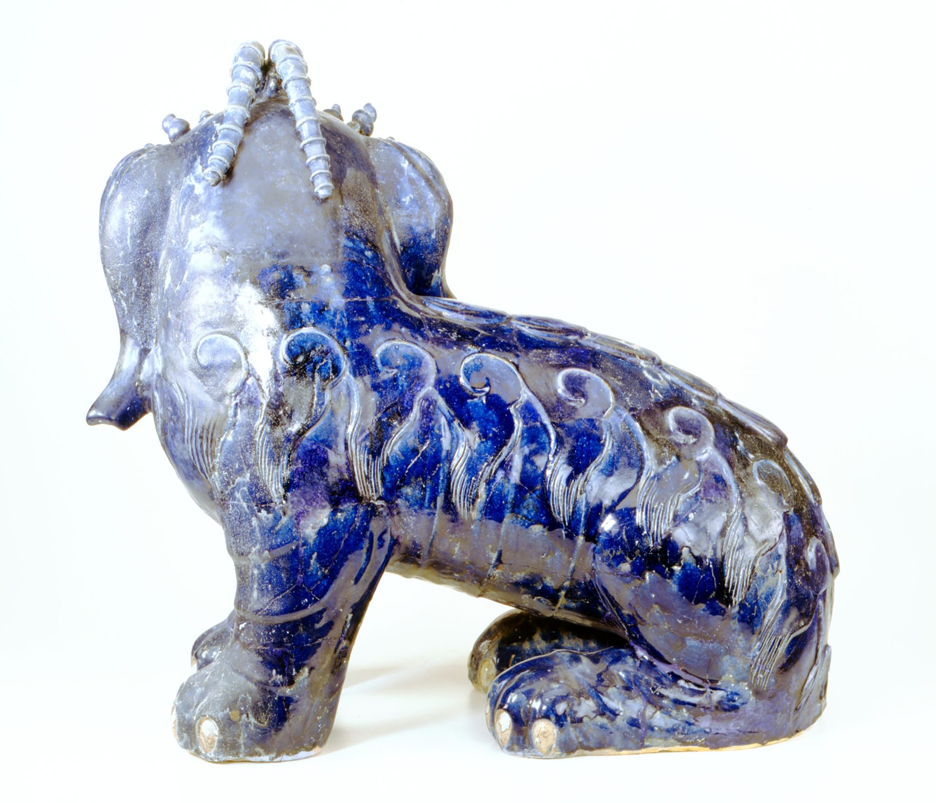 Blauer Löwe mit kunstvollen Ornamenten und geschwungenem Schwanz, seitliche Ansicht.