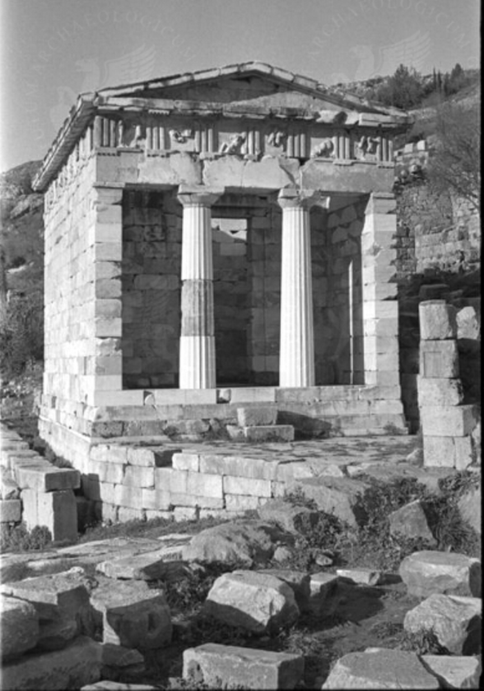 Antiker Tempel mit Säulen und Ruinen, umgeben von grünem Bewuchs unter einem klaren Himmel.