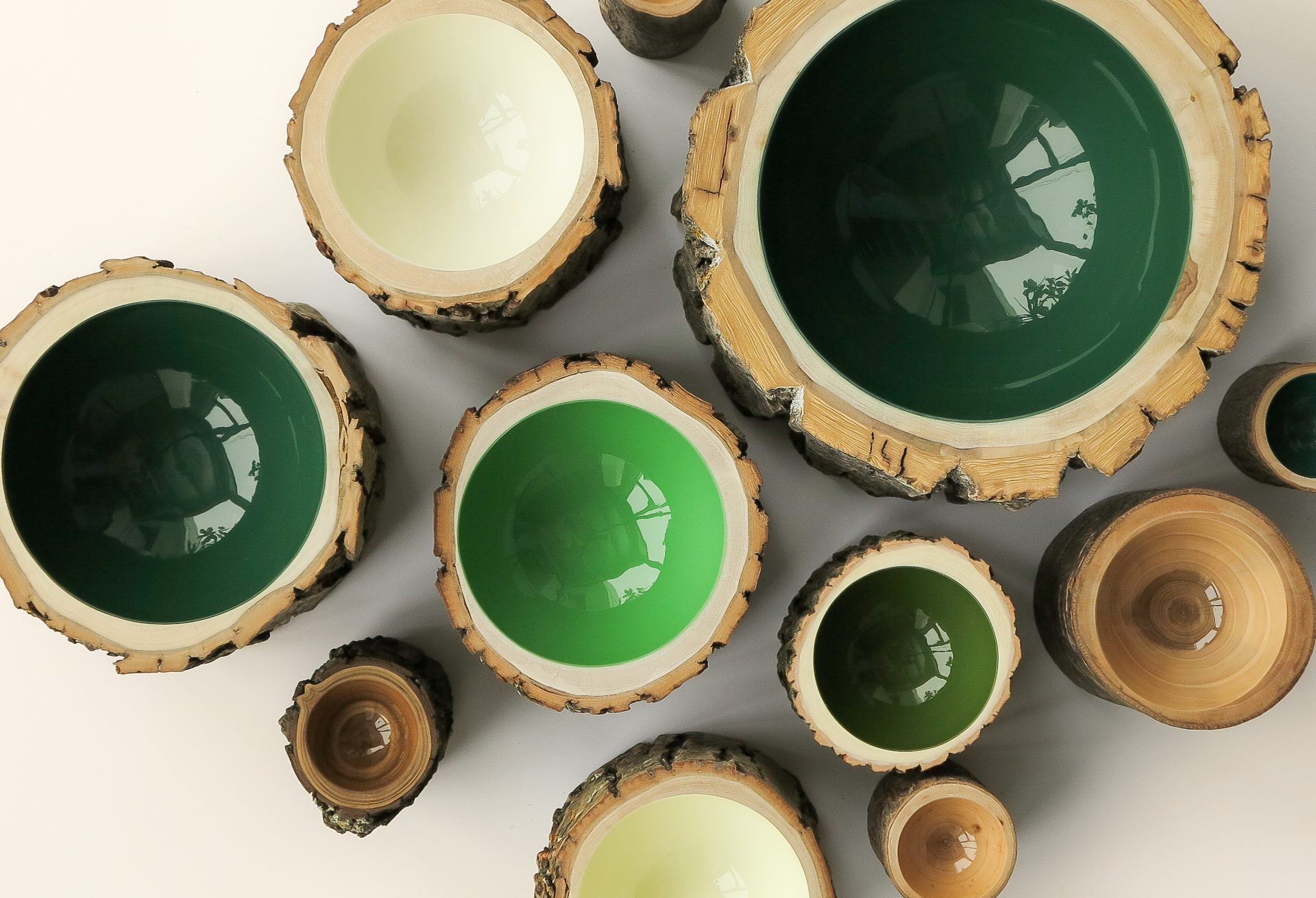 Holzschalen in verschiedenen Grüntönen und Größen, stilvoll auf einem hellen Hintergrund arrangiert.
