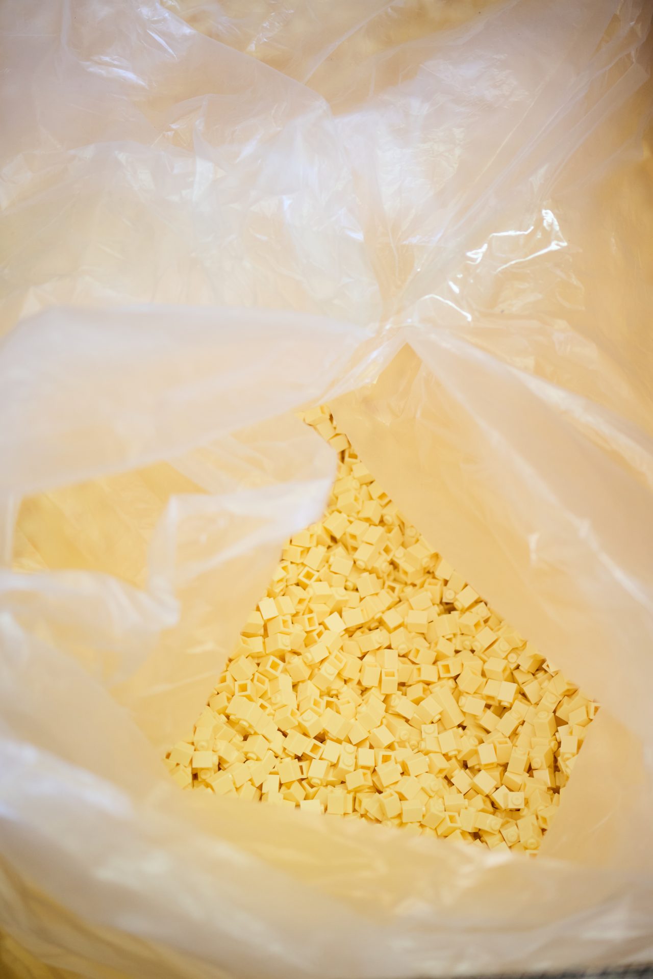 Gelbe, quadratische Kunststoffteile befinden sich in einer durchsichtigen Plastiktüte.